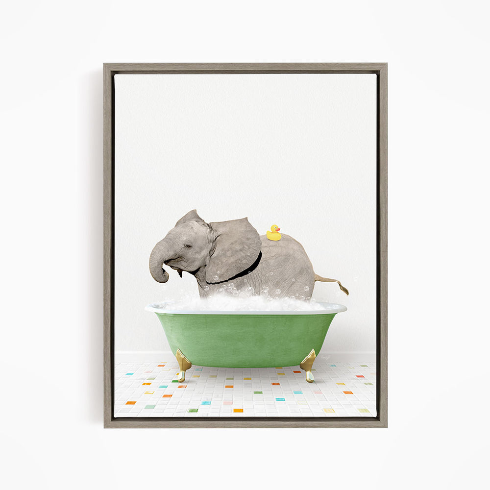 A gray elephant is sitting in a green bathtub filled with bubbles, with a yellow rubber duck floating on its back.