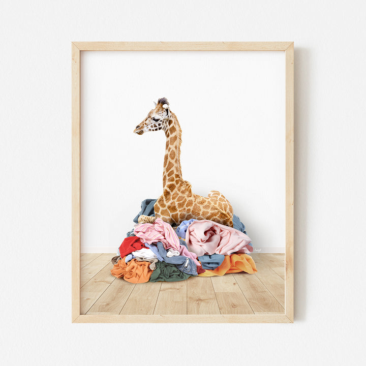 a giraffe sitting on top of a pile of clothes