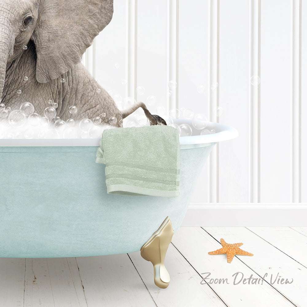 A baby elephant is sitting in a light blue bathtub filled with bubbles, with a green towel hanging on the side and a starfish nearby.