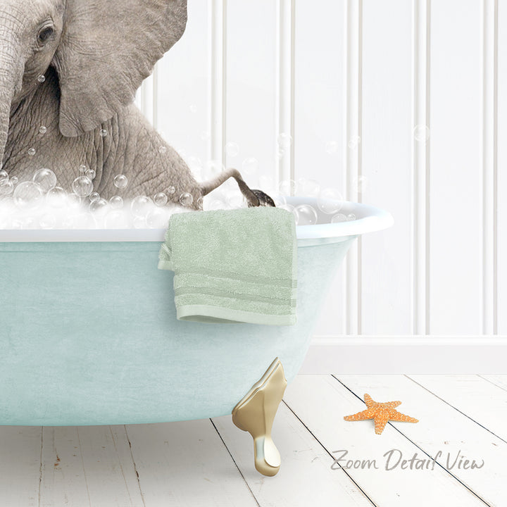 A baby elephant is sitting in a light blue bathtub filled with bubbles, with a green towel hanging on the side and a starfish nearby.