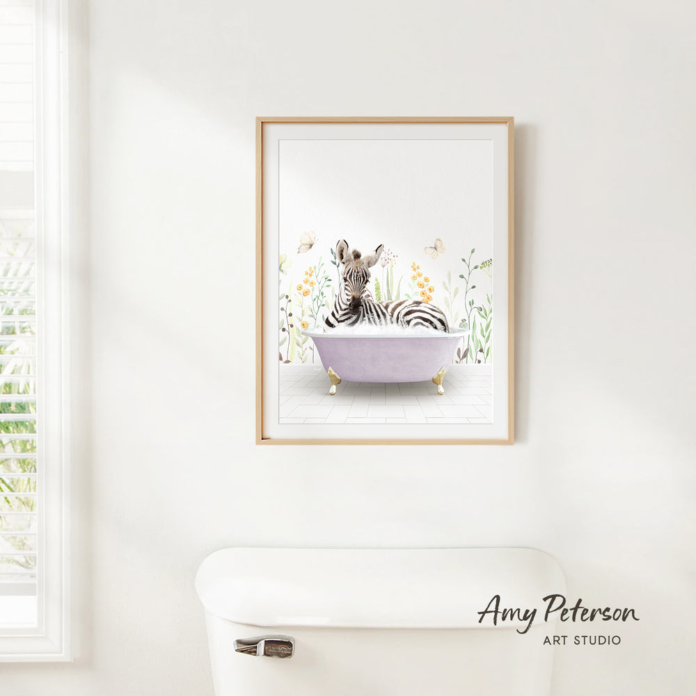 A framed print of a zebra sitting in a bathtub is hanging on a white wall in a bathroom.