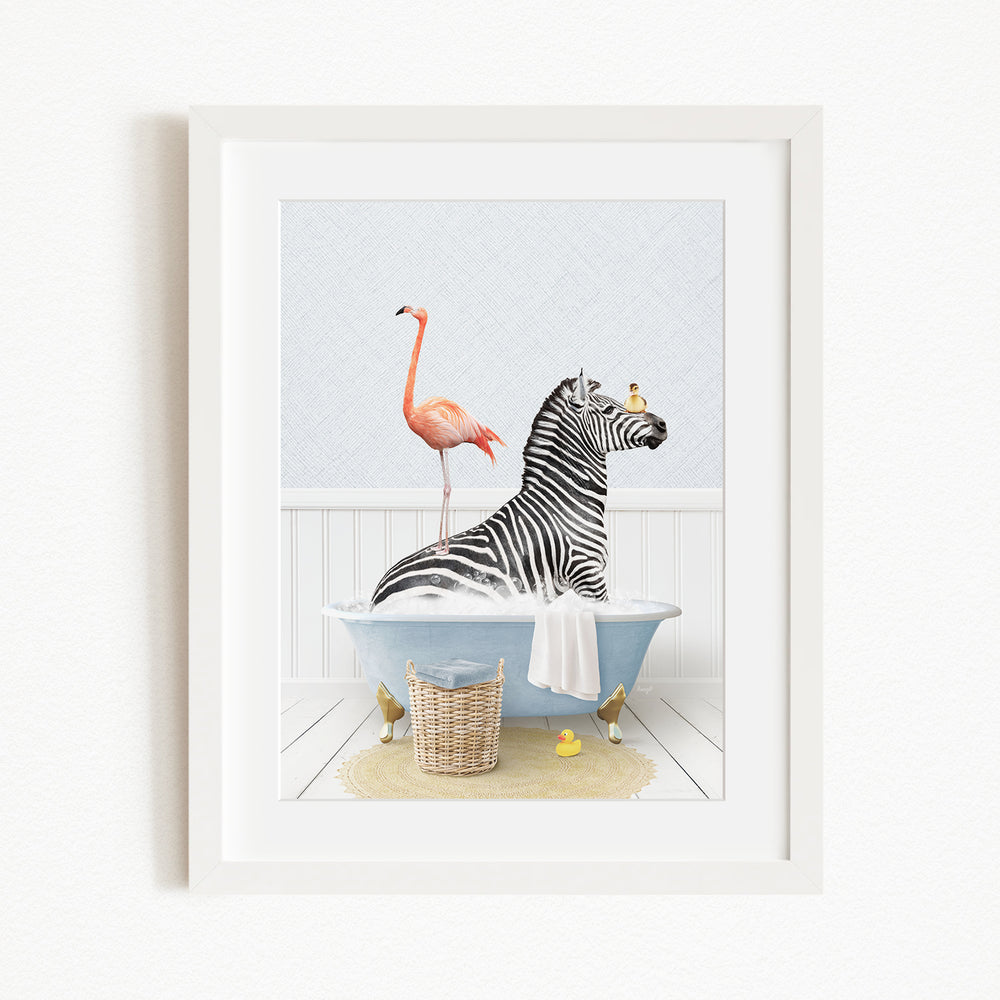A framed image depicting a zebra sitting in a bathtub, with a pink flamingo standing on its back and a basket of rubber ducks nearby.