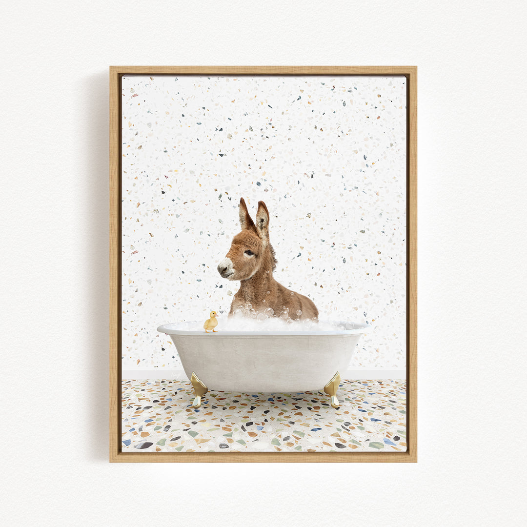 A donkey is sitting in a bathtub filled with water, surrounded by small yellow rubber ducks.