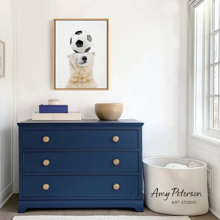 a blue dresser with a framed picture of a polar bear balancing a soccer ball on its head. The dresser is situated in a room with white walls and a window.