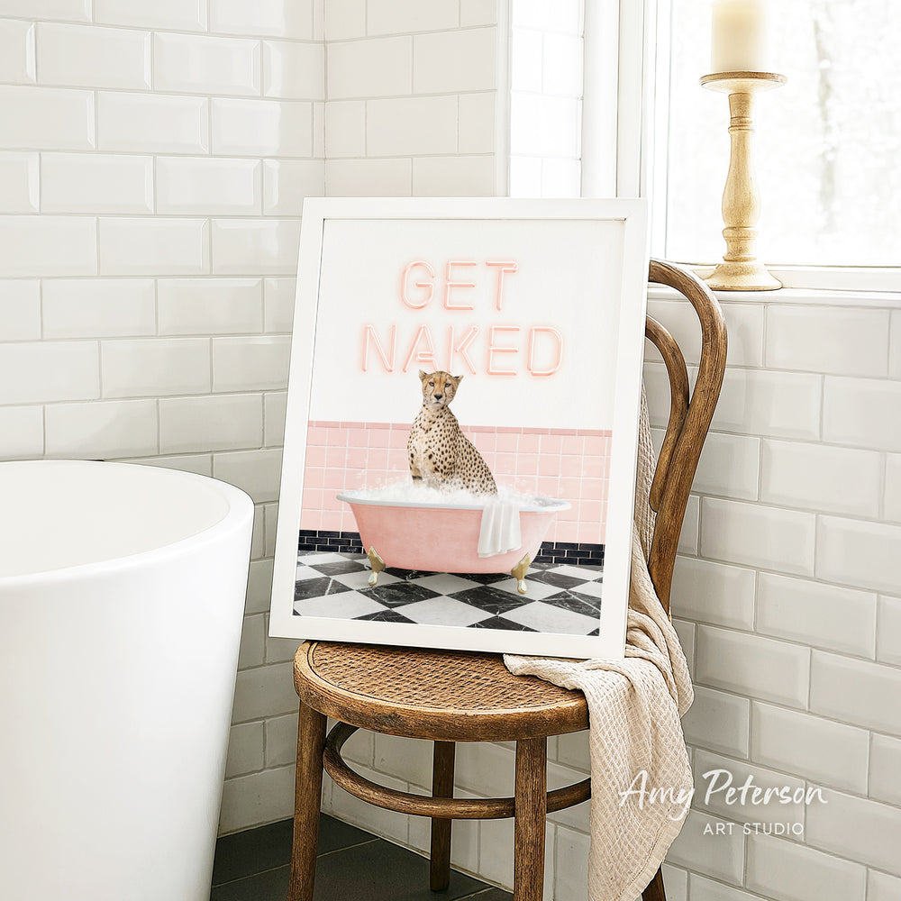 A framed print with a cheetah sitting in a pink bathtub, with the text "GET NAKED" displayed on the frame.