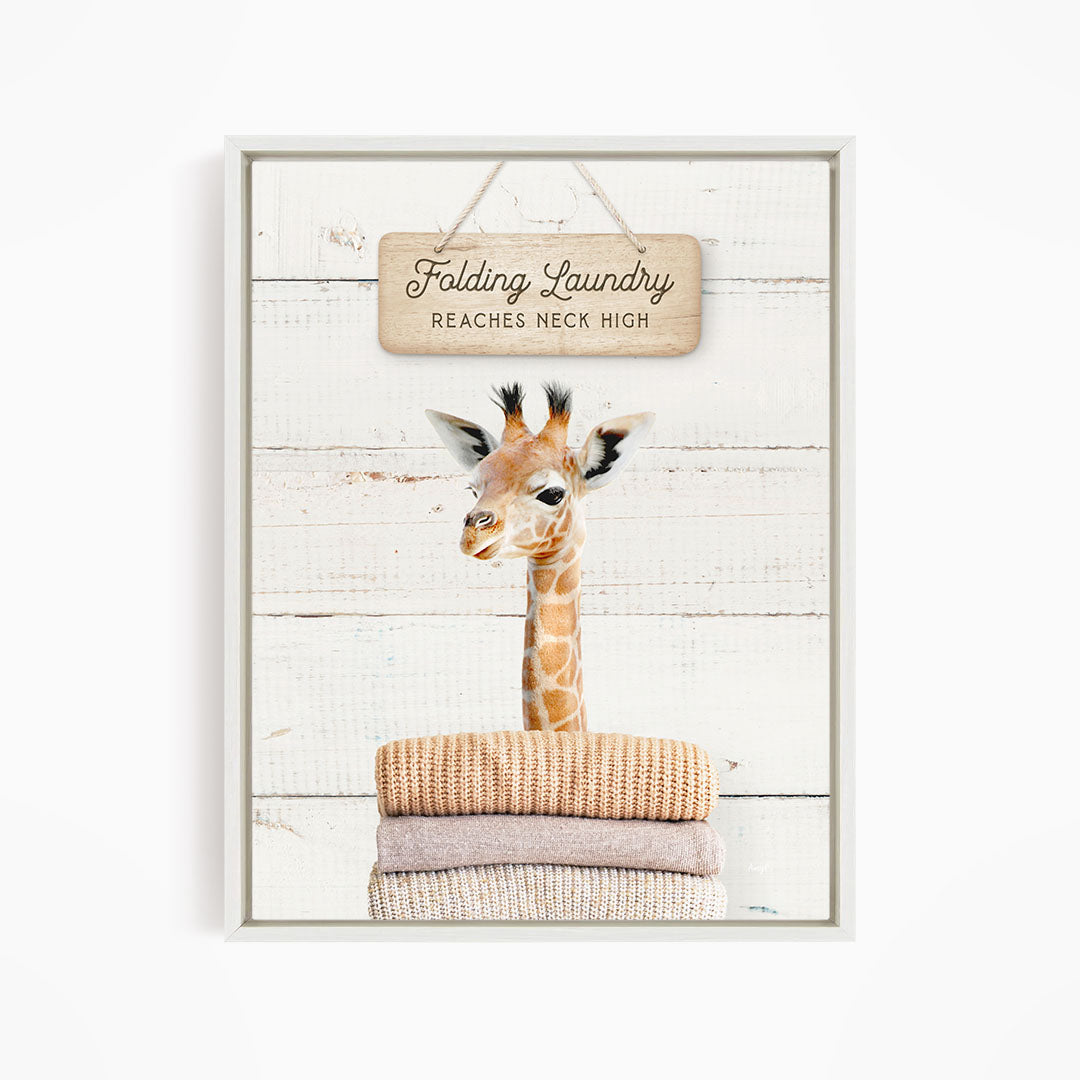 A giraffe standing on a pile of folded clothes, with a sign above that says "Folding Laundry Reaches Neck High".