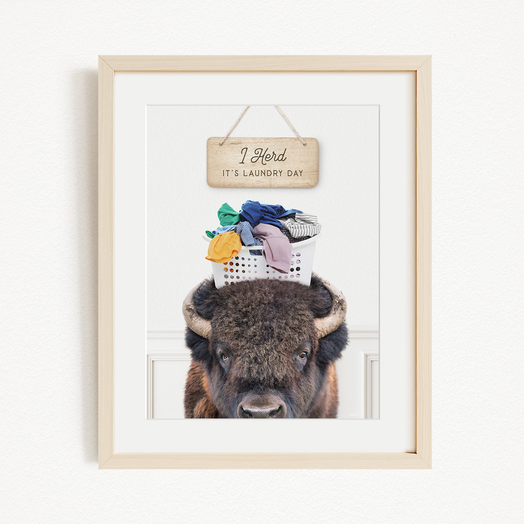 A buffalo with a laundry basket on its head, accompanied by a wooden sign that says "I Harded It's Laundry Day".