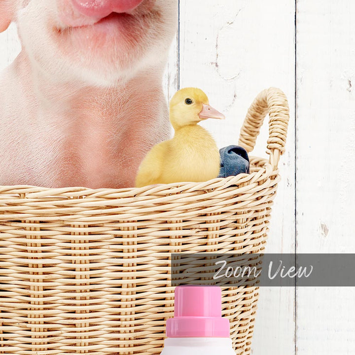 A small yellow duckling peeks out from a wicker basket, with a pink bottle and a white wall in the background.