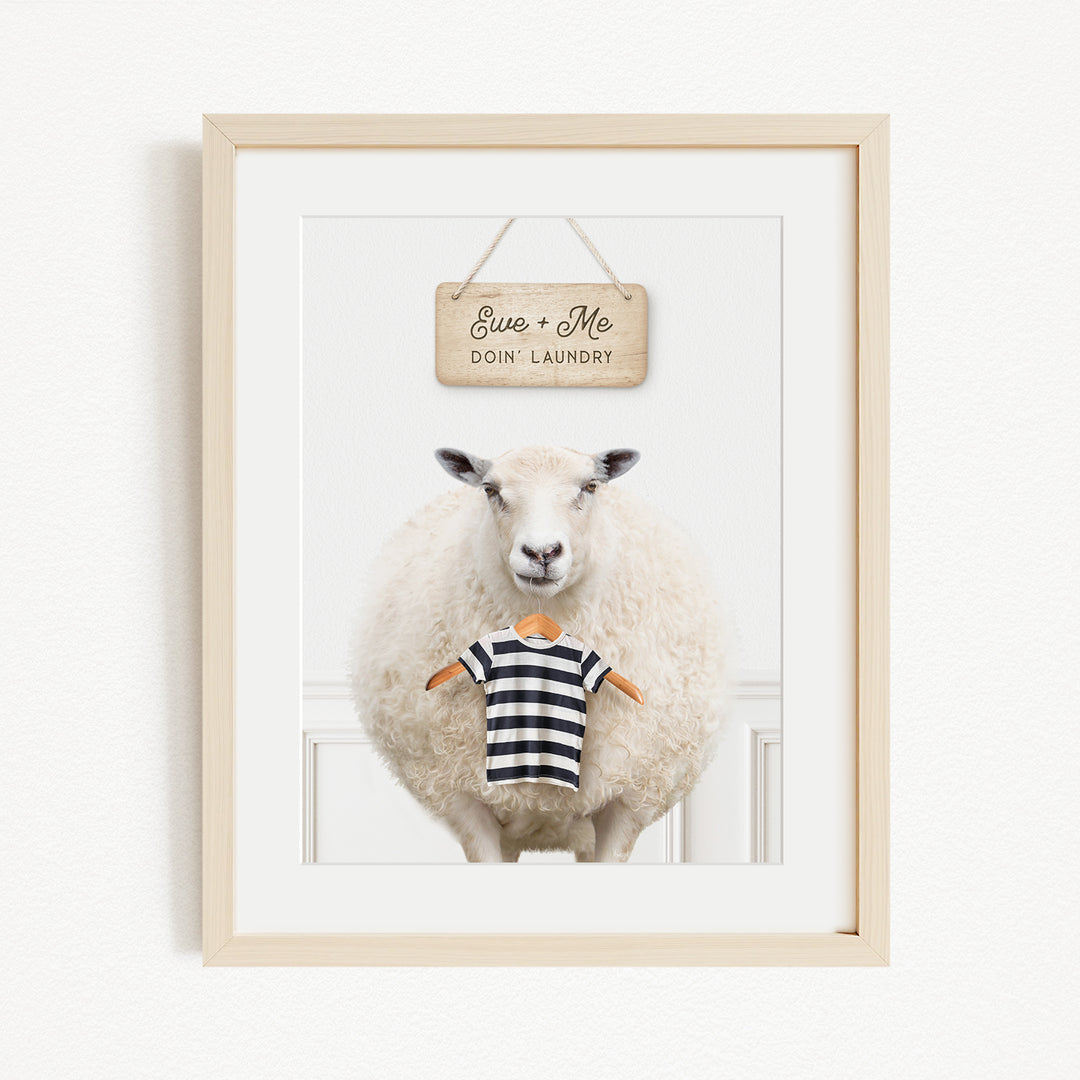 A framed image of a sheep wearing a striped shirt, with a sign above it that says "Eee + Me Doin Laundry".