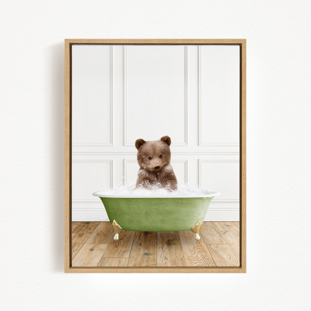 A small brown bear cub sitting in a green bathtub filled with water, looking at the camera.