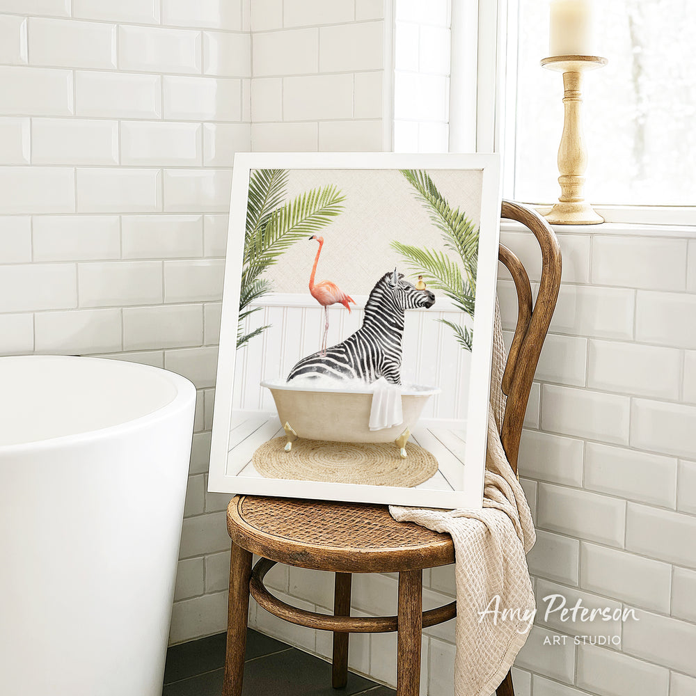 A framed painting of a zebra sitting in a bathtub, surrounded by tropical plants, is displayed on a wooden chair in a bathroom setting.