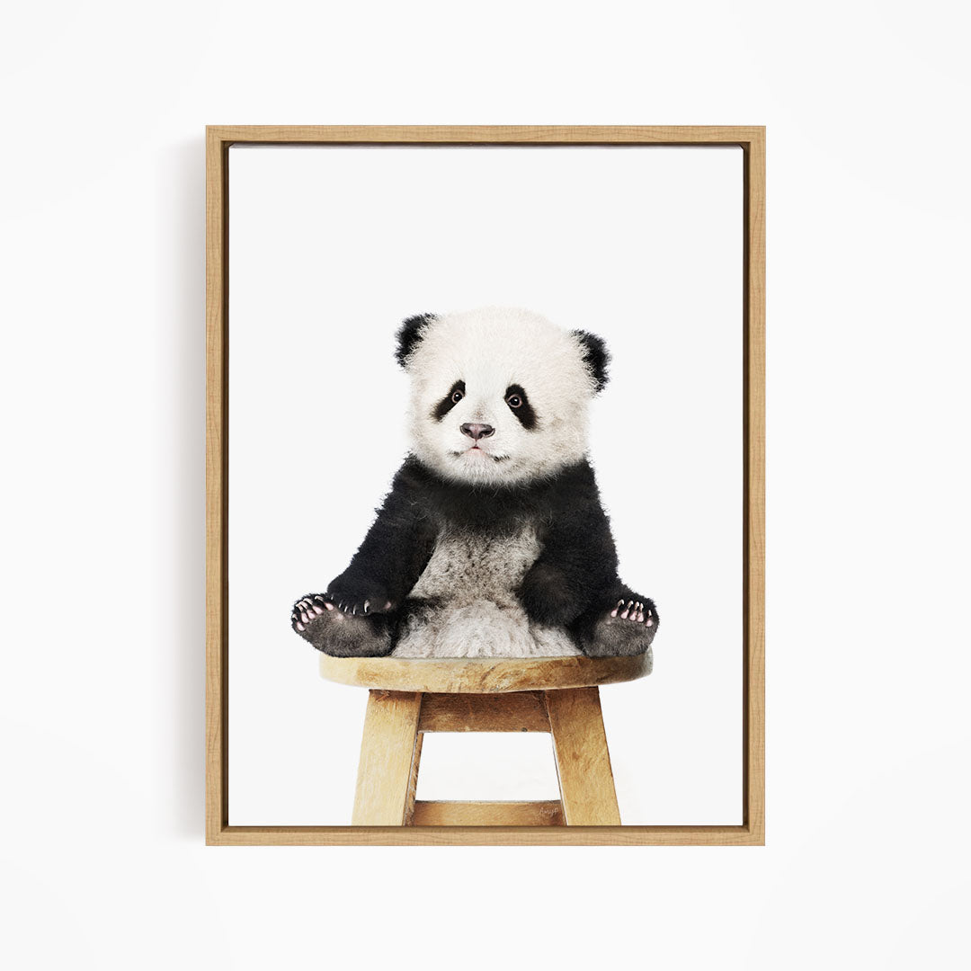 A cute panda sitting on a wooden stool.
