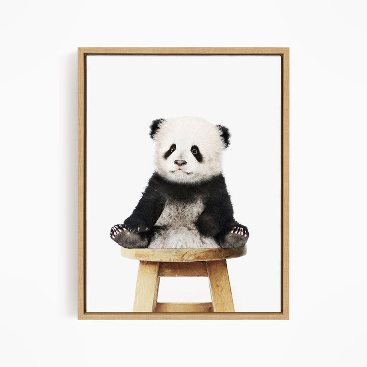 A cute panda sitting on a wooden stool.
