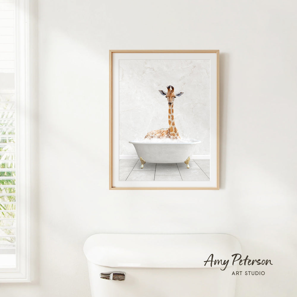 A framed painting of a giraffe sitting in a bathtub is hanging on a white wall.