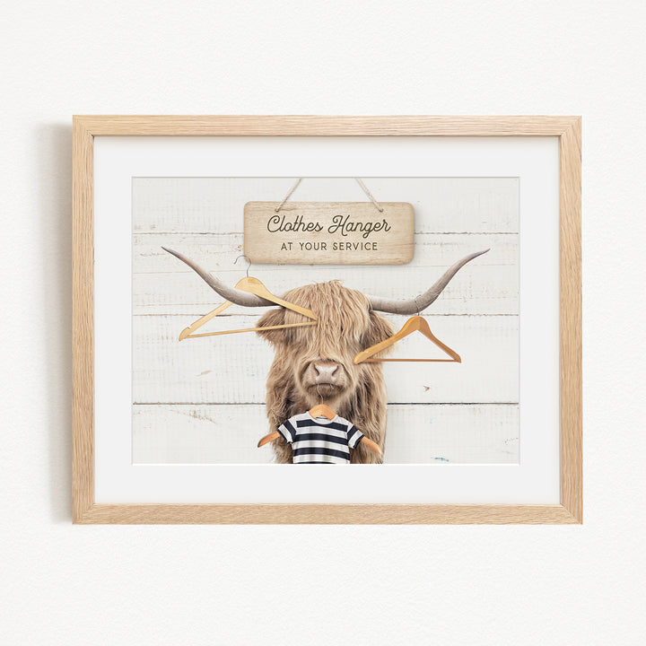 A framed image depicting a large, furry animal with long horns, wearing a striped shirt and surrounded by hanging clothes hangers.