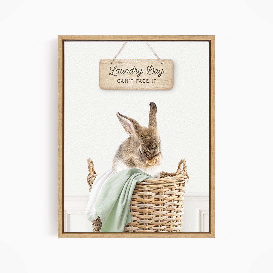 A wooden sign with the text "Laundry Day Can't Face It" hangs above a woven basket containing a rabbit.