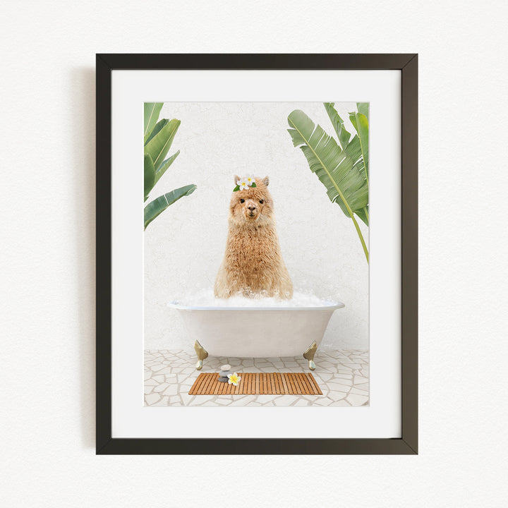 A brown alpaca sitting in a white bathtub, surrounded by green plants, with a wooden mat on the floor in front of the tub.