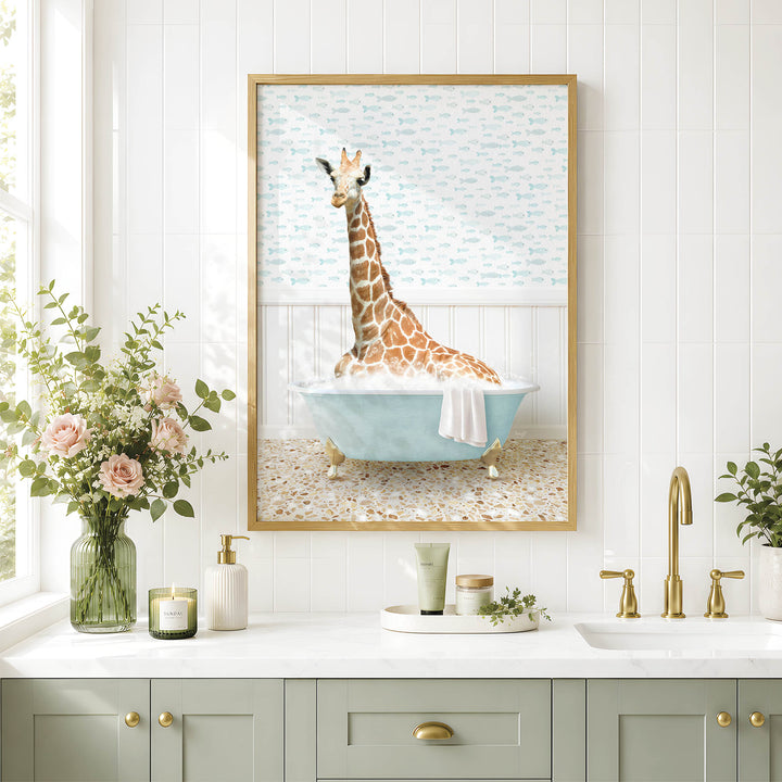 A giraffe sitting in a blue bathtub, surrounded by flowers and a framed picture on a white tiled wall.
