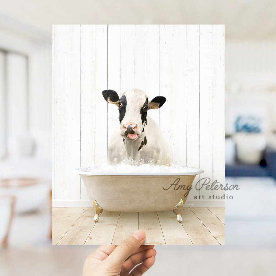 a hand holding up a photo of a cow in a bathtub