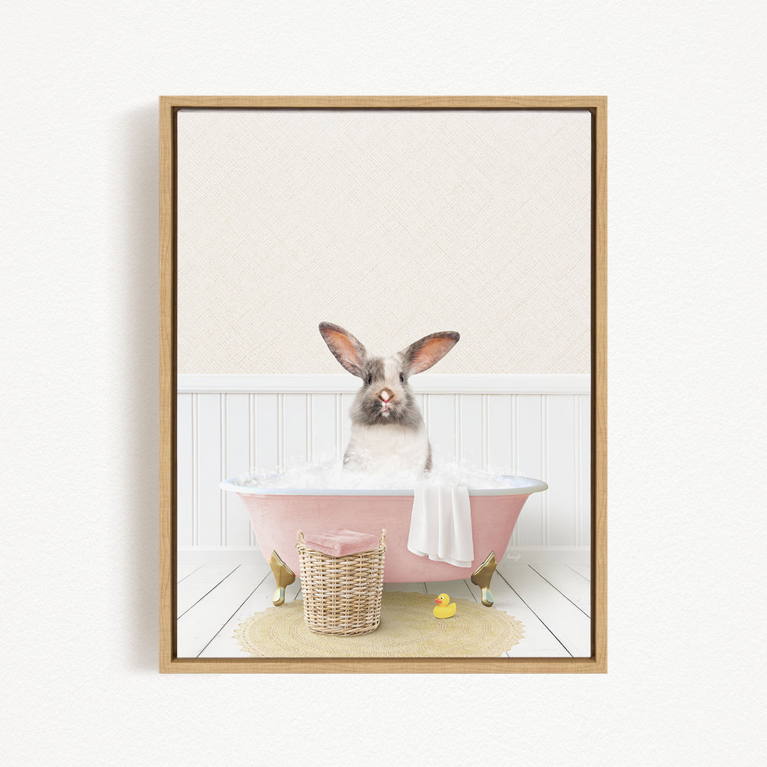 A fluffy white rabbit sits in a pink bathtub filled with bubbles, surrounded by a yellow rubber duck and a wicker basket.