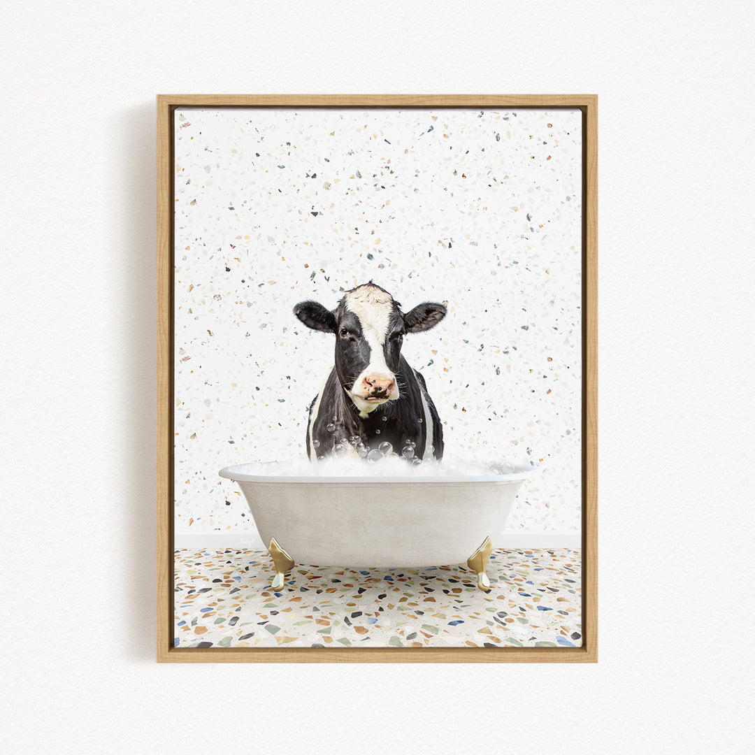 A black and white cow is sitting in a white bathtub filled with water, creating a whimsical and playful scene.
