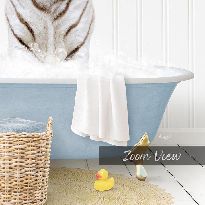 A white cat is sitting in a blue bathtub filled with bubbles, with a yellow rubber duck nearby and a basket of towels on the floor.