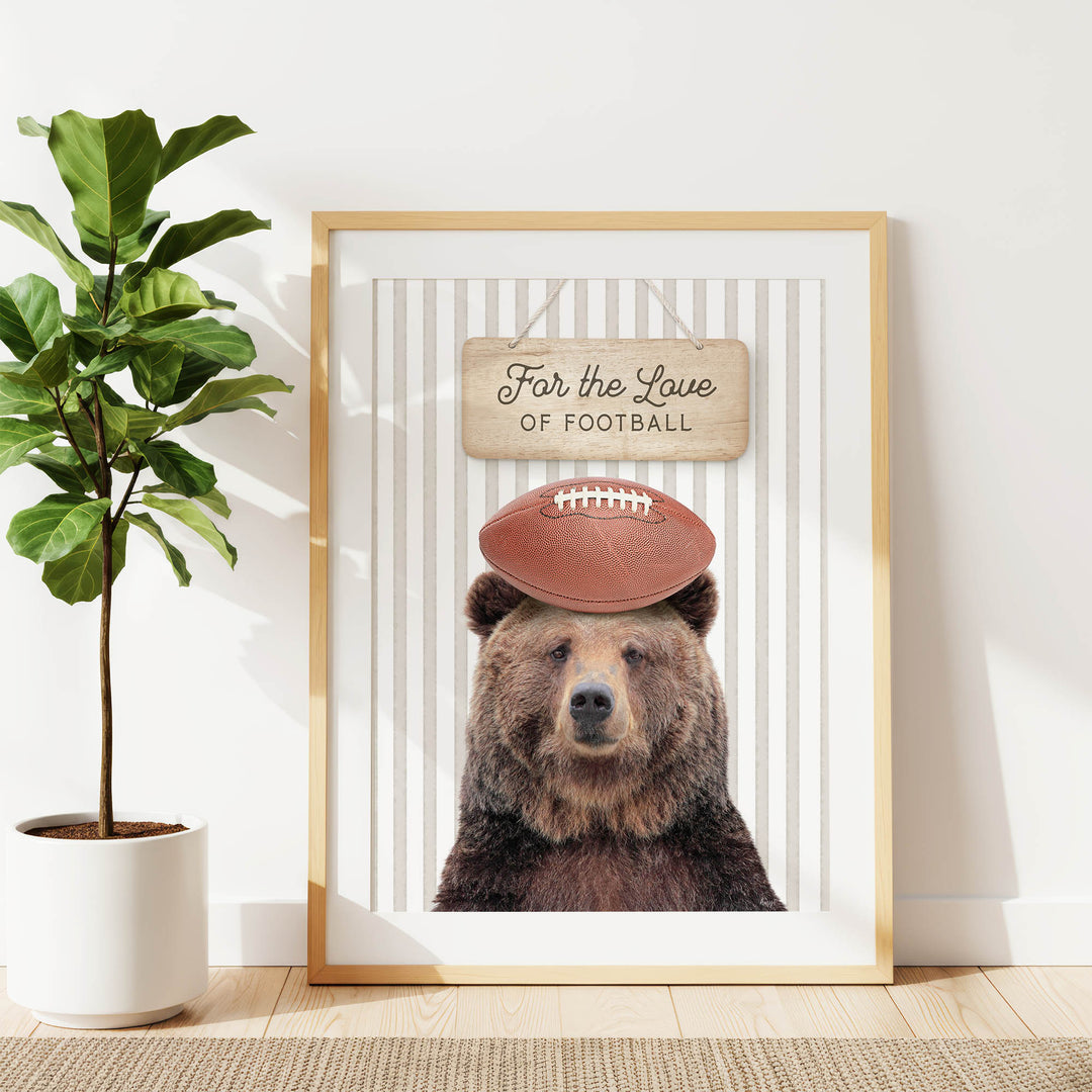 A framed print of a bear wearing a football helmet, with the text "For the Love of Football" written on the sign above the bear's head.