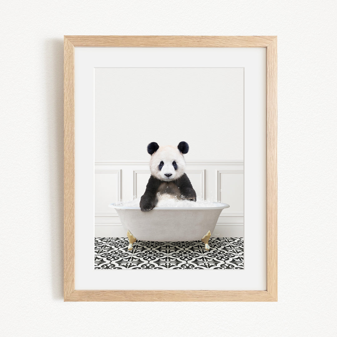A panda bear sitting in a white bathtub filled with bubbles, surrounded by a black and white patterned rug.