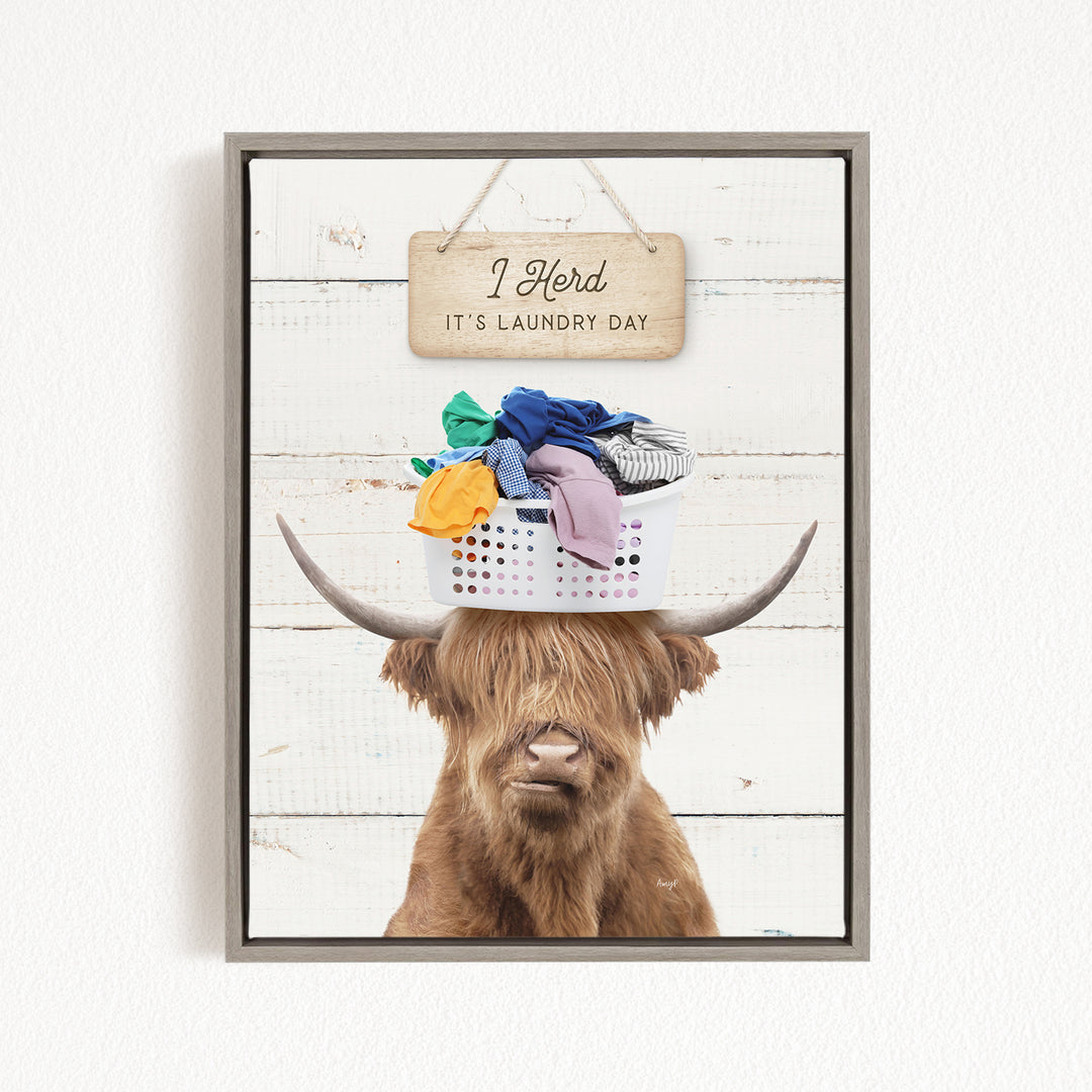 A humorous image of a Highland cow with a basket of laundry on its head, accompanied by a wooden sign that reads "I herd it's laundry day".