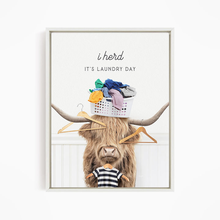 A framed image depicting a long-haired cow with a basket of laundry on its head, accompanied by the text "It's Laundry Day" and a humorous caption.