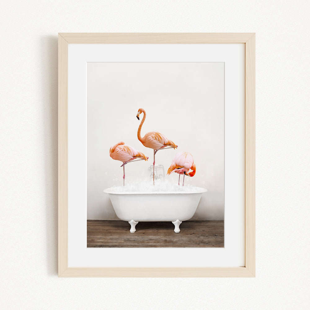 A framed image depicting three flamingos standing in a white bathtub filled with water.