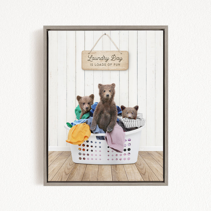 A framed image of three bears sitting in a laundry basket, with a sign above them that says "Laundry Day is loads of fun".