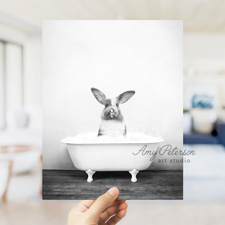 a person holding up a photo of a rabbit in a bathtub