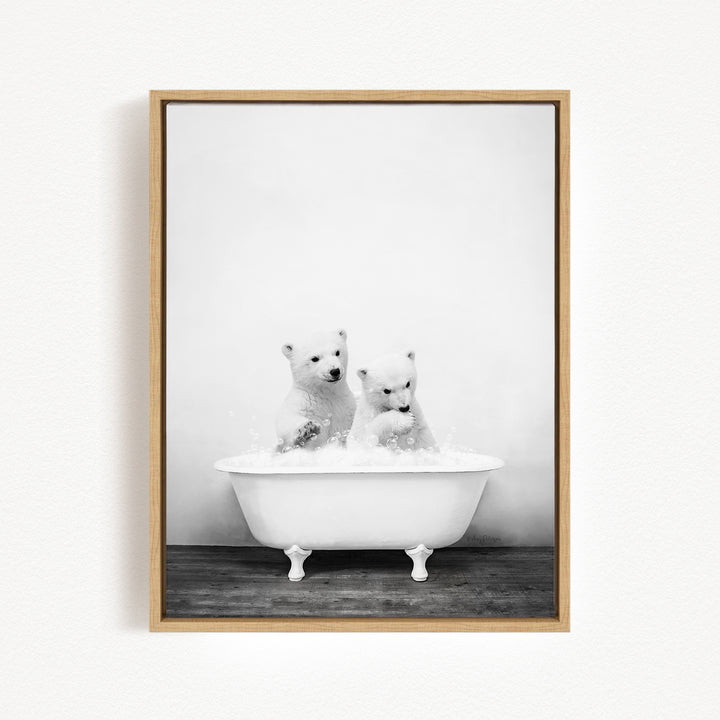 Two adorable polar bears enjoying a bath in a white bathtub.