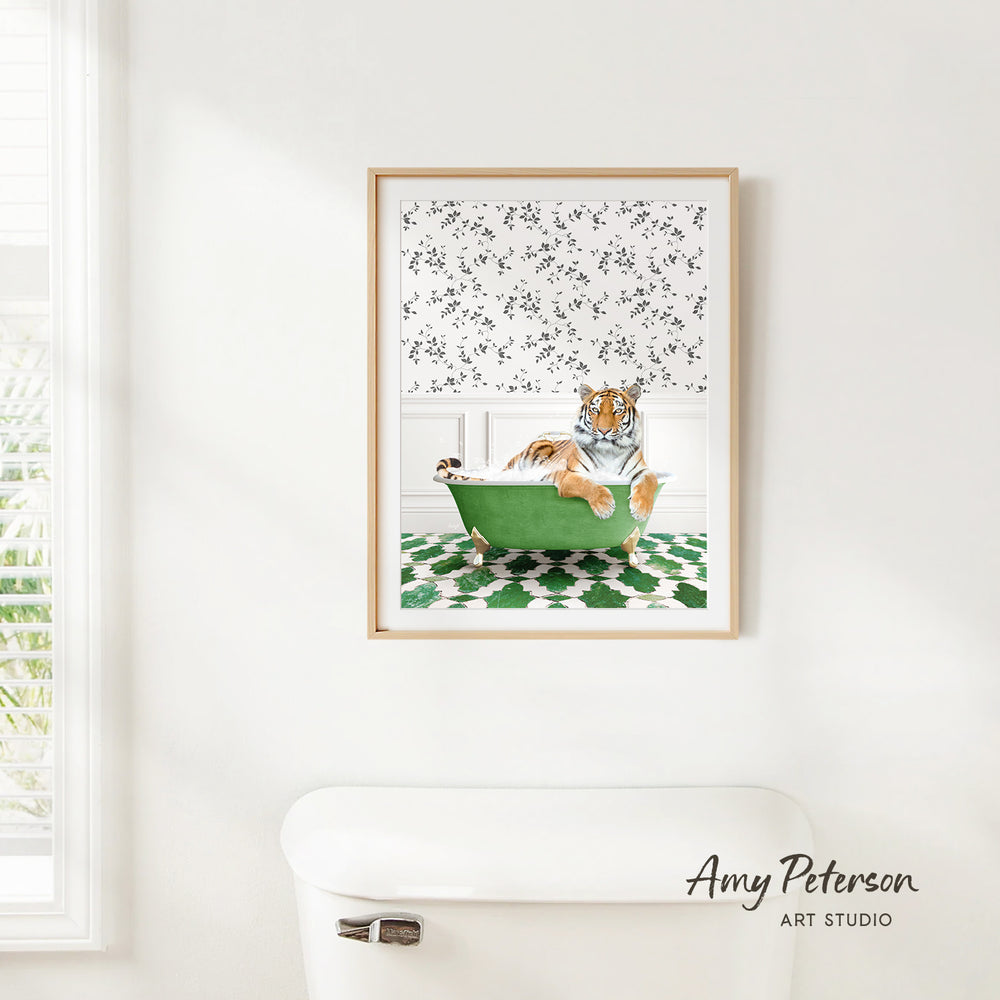A framed print of a tiger sitting in a green bathtub is hanging on a white wall in a bathroom.