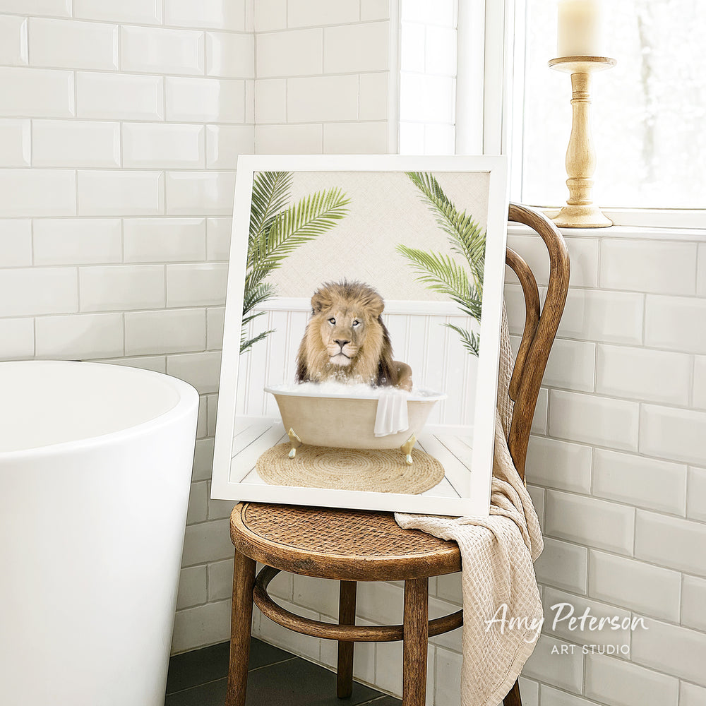 A framed image of a lion sitting in a bathtub, surrounded by palm leaves, is displayed on a wooden chair in a bathroom setting.