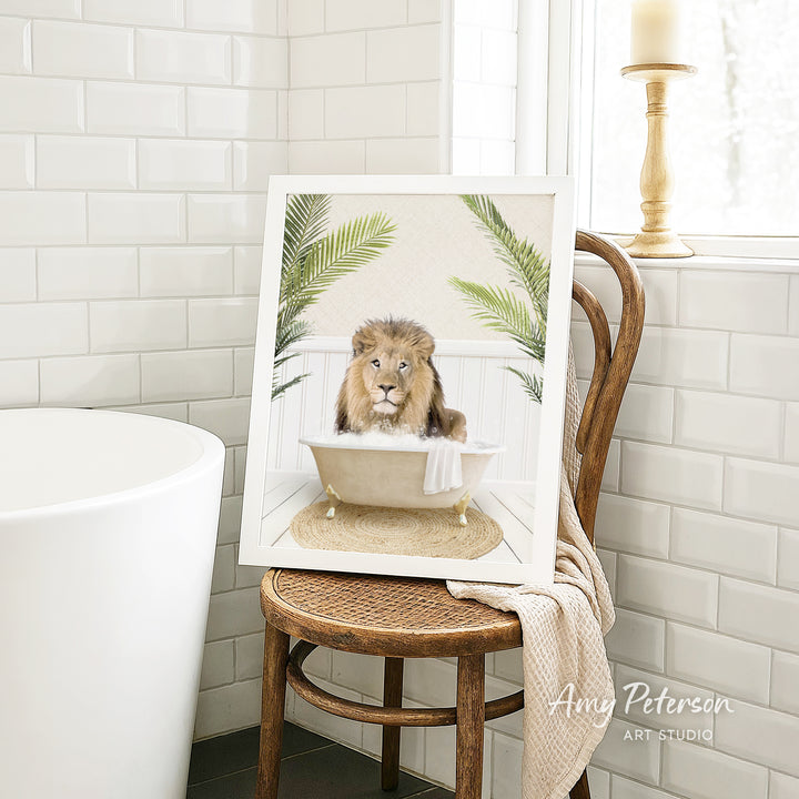 A framed image of a lion sitting in a bathtub, surrounded by palm leaves, is displayed on a wooden chair in a bathroom setting.
