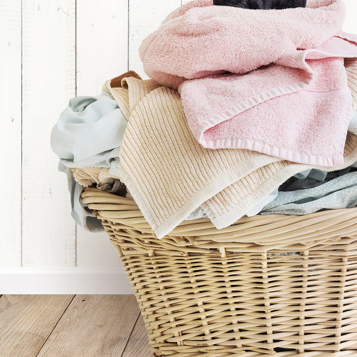 a wicker basket filled with clothes on a wooden floor