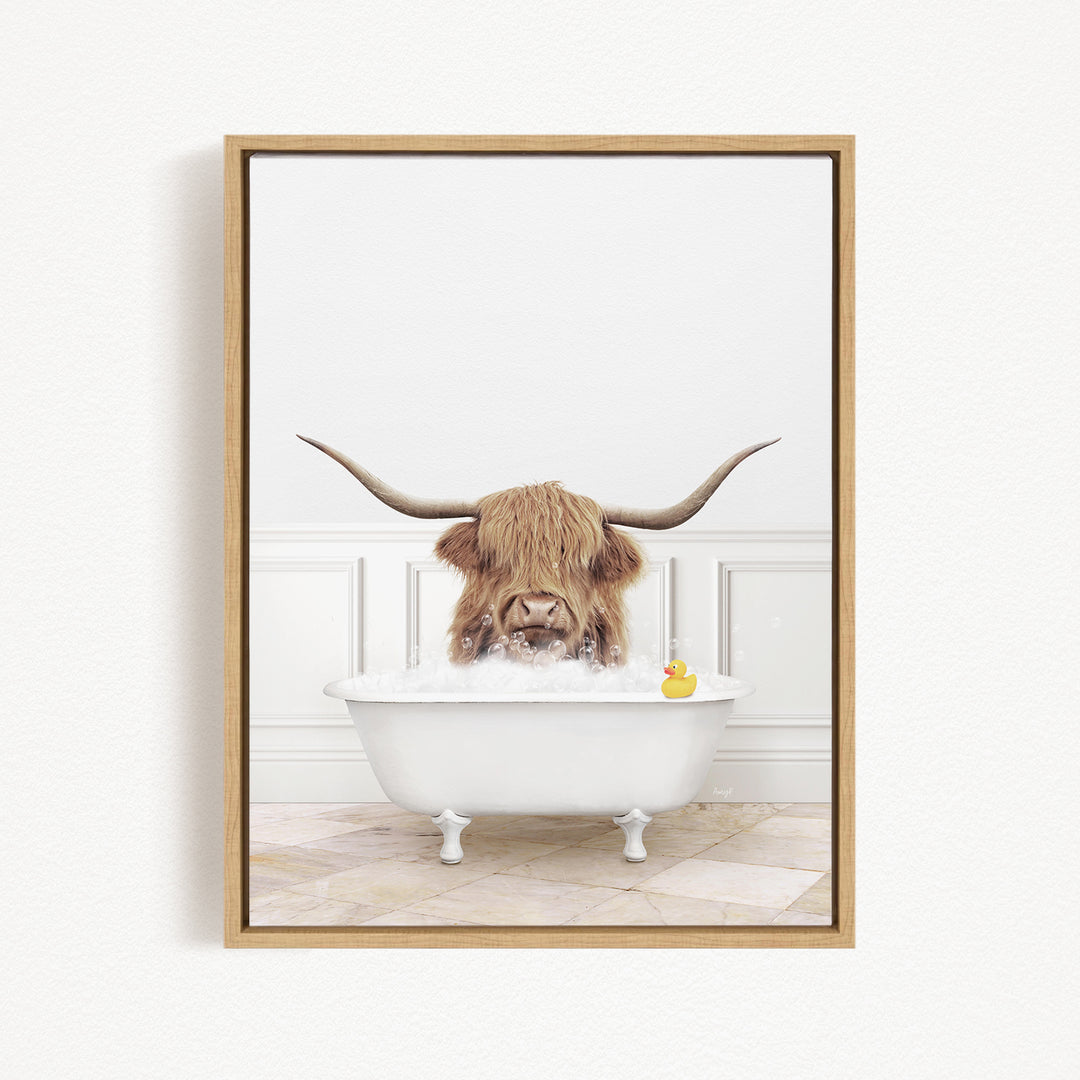 A long-haired cow with large horns is sitting in a white bathtub, surrounded by a yellow rubber duck.