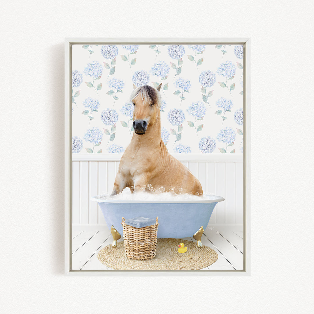A light brown horse is sitting in a blue bathtub filled with water, surrounded by a wicker basket and a yellow rubber duck.
