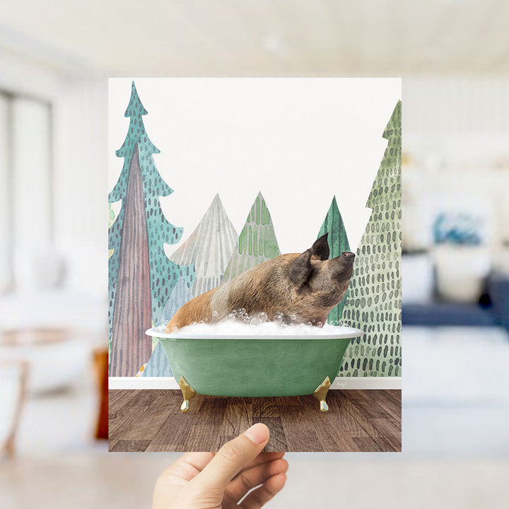 A hand holds up a framed image depicting a pig sitting in a green bathtub, surrounded by a forest scene with trees and a blue sky.