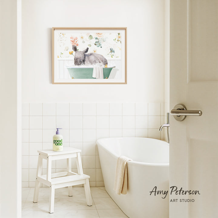 A bathroom interior with a white bathtub, a stool, and a framed painting of a rabbit in a bathtub on the wall.