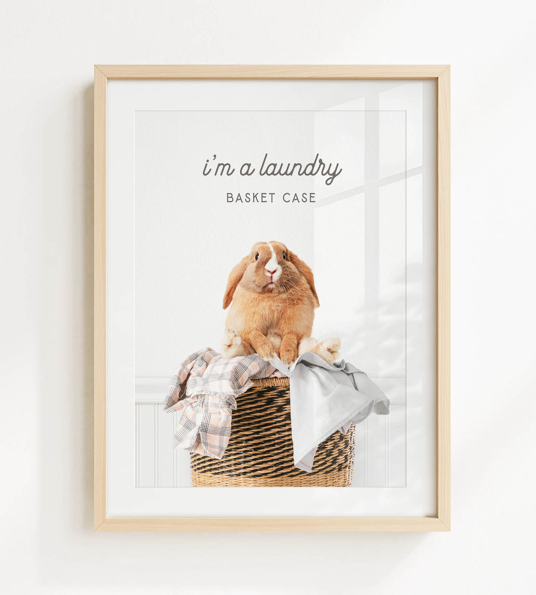A framed image of a rabbit sitting in a laundry basket, with the text "I'm a laundry Basket Case" displayed above the rabbit.