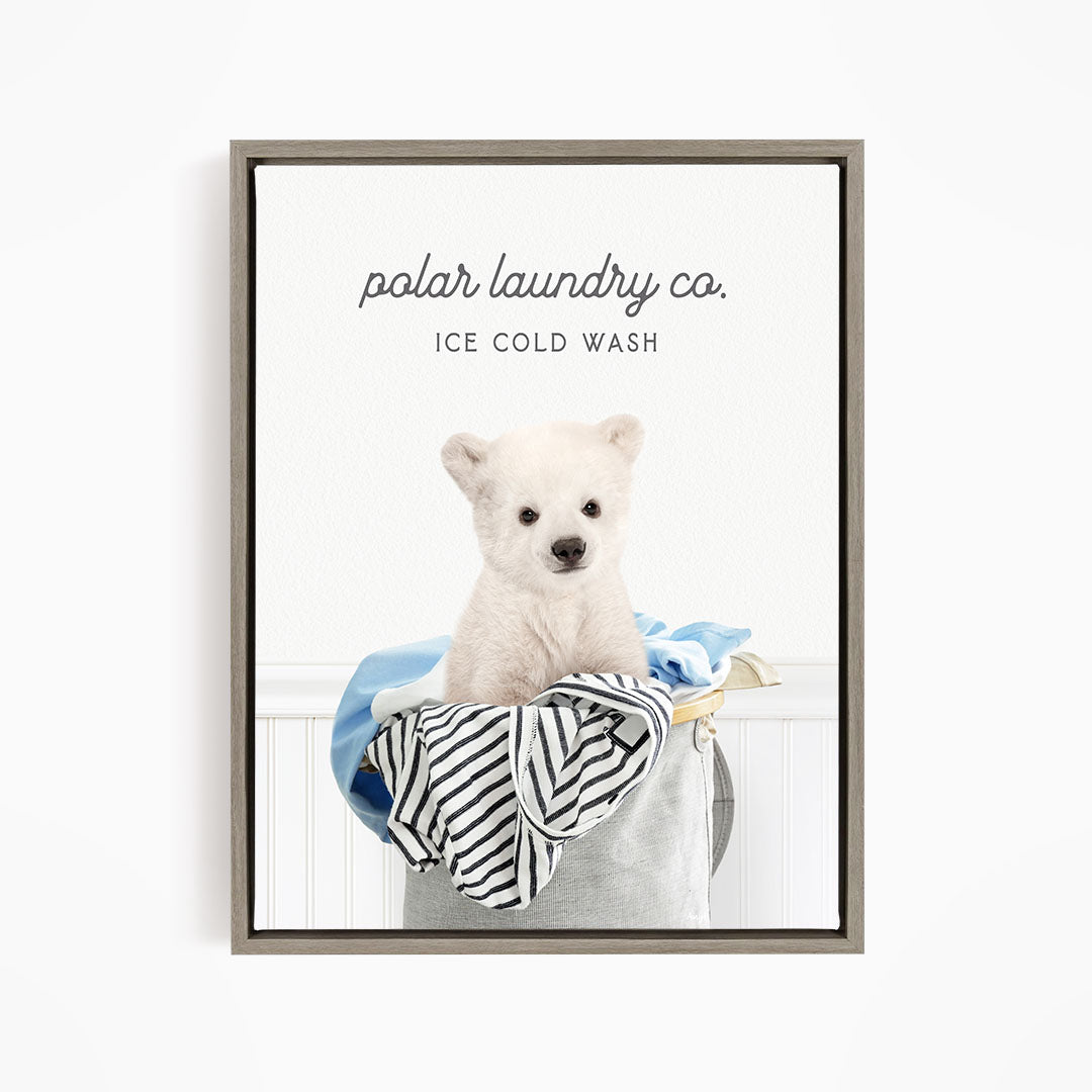 A white polar bear sitting in a laundry basket filled with clothes, with the text "polar laundry co. ICE COLD WASH" displayed above the image.