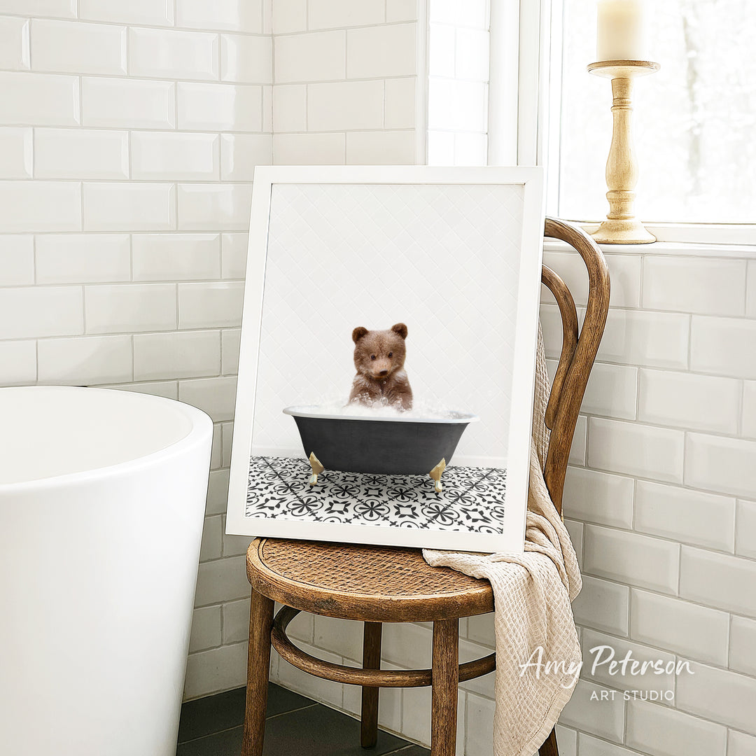 A framed image of a teddy bear sitting in a bathtub, surrounded by a patterned tile design, is displayed on a wooden chair in a bathroom setting.