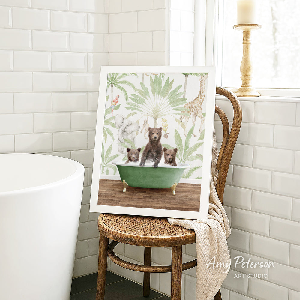 A framed print of three bears sitting in a green bathtub is displayed on a wooden chair in a bathroom setting.
