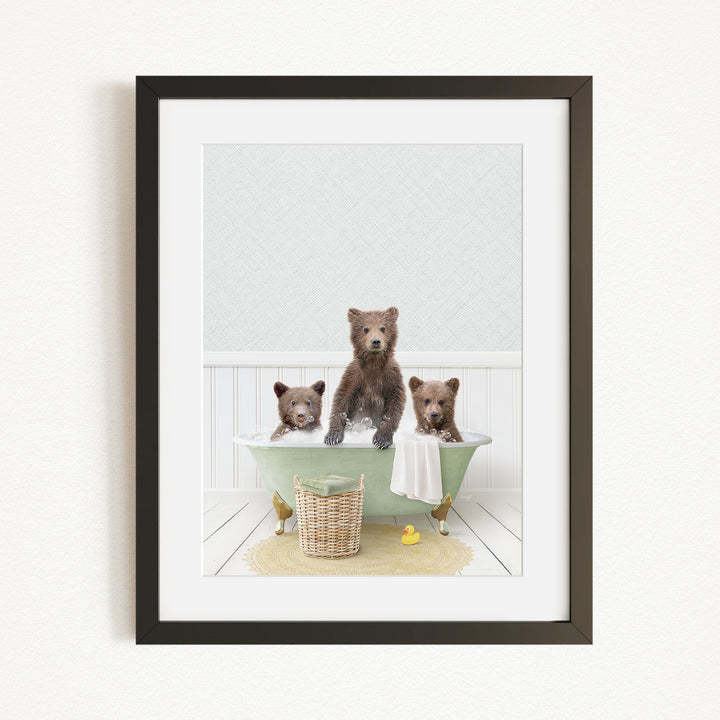 A framed image depicting three brown bears sitting in a green bathtub, with a basket of bath toys nearby.