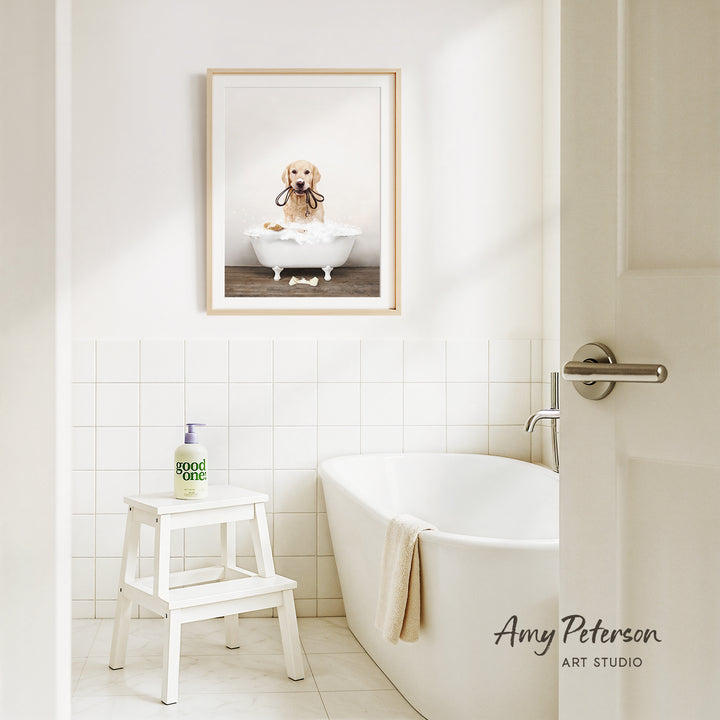A framed image of a dog sitting in a bathtub, with a towel draped over the side of the tub, is displayed on the wall above a white bathtub in a clean, white-tiled bathroom.