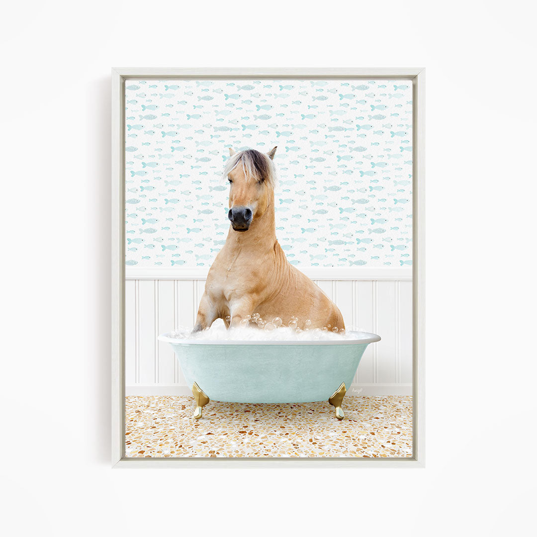 A light brown horse is sitting in a blue bathtub filled with water, surrounded by a pattern of small fish.