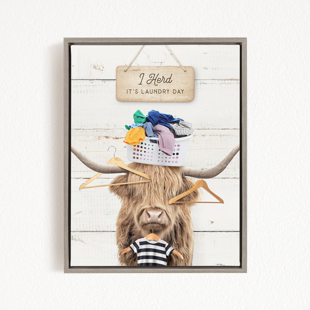 A framed image depicting a cow with a sign above it that says "I herd it's laundry day", and a basket of clothes on its head.